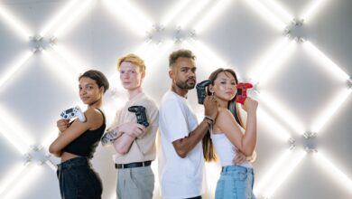 Four diverse friends posing confidently with game controllers against a modern LED backdrop.