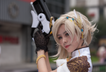 Cosplayer with intricate costume and prop gun, posing outdoors during the day.