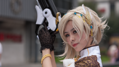 Cosplayer with intricate costume and prop gun, posing outdoors during the day.