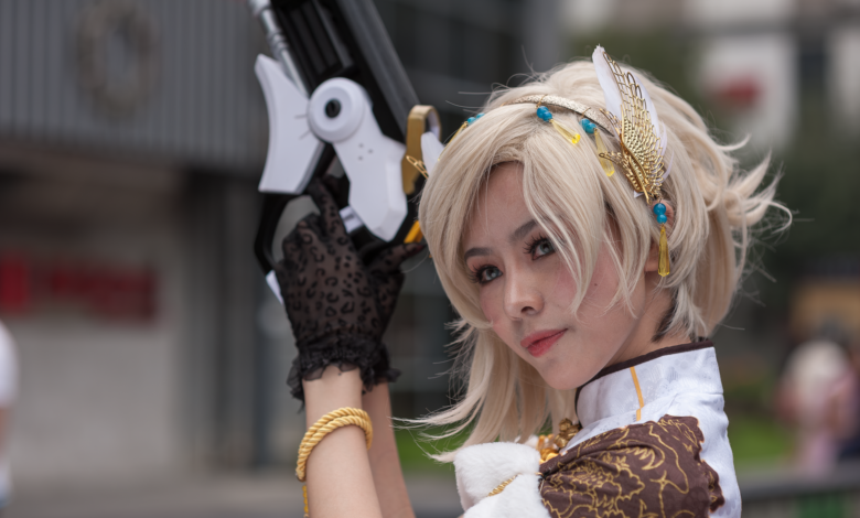 Cosplayer with intricate costume and prop gun, posing outdoors during the day.