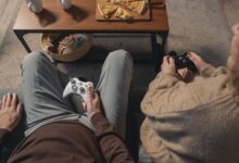 Elderly couple playing video games on the sofa, enjoying leisure time with a console.