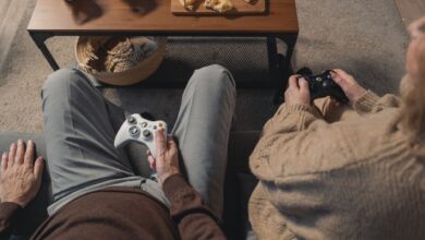 Elderly couple playing video games on the sofa, enjoying leisure time with a console.