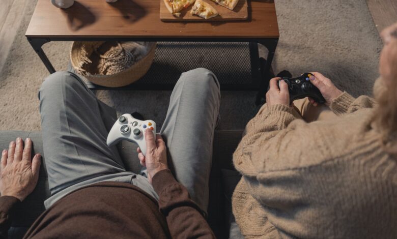 Elderly couple playing video games on the sofa, enjoying leisure time with a console.