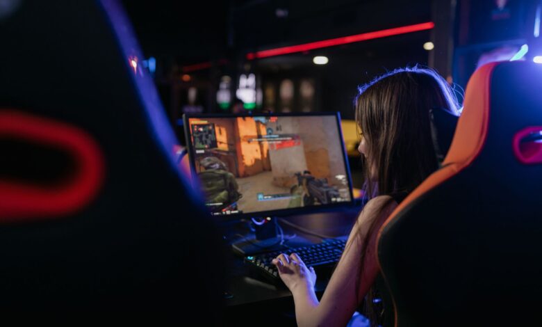 A woman is deeply engaged in playing computer games indoors, highlighting the gaming lifestyle.