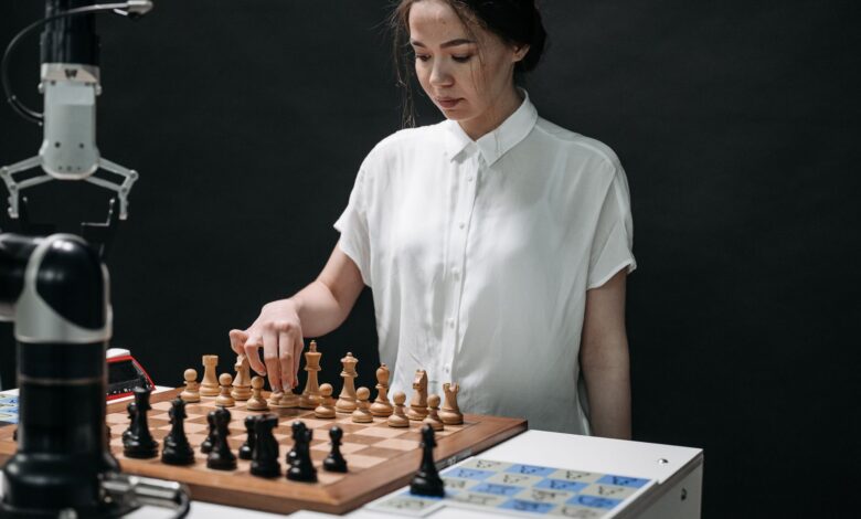 A woman plays chess with a robotic arm, illustrating technology and strategy in a modern context.