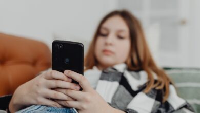 Teenage girl using smartphone while relaxing on a sofa, depicting leisure and connectivity.