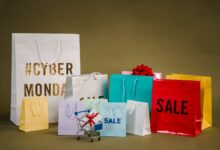 Colorful shopping bags with Cyber Monday and sale text, featuring a mini cart with gifts.