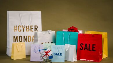 Colorful shopping bags with Cyber Monday and sale text, featuring a mini cart with gifts.