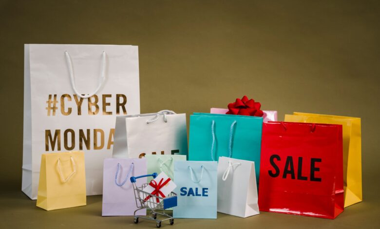 Colorful shopping bags with Cyber Monday and sale text, featuring a mini cart with gifts.
