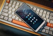 Close-up of a smartphone lying on a vintage mechanical keyboard, showcasing a modern interface.