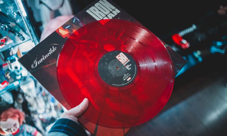 From above crop person holding red vinyl disc with inscription cover in music shop