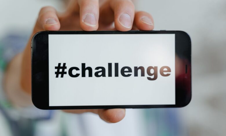 Close-up of a hand holding a smartphone displaying a '#challenge' hashtag.