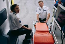 Two paramedics prepare a stretcher inside an ambulance, ready for an emergency response.