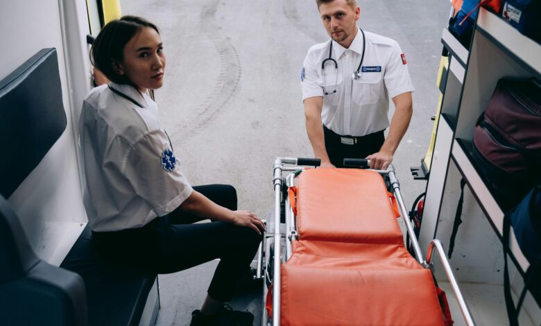 Two paramedics prepare a stretcher inside an ambulance, ready for an emergency response.