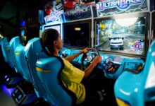 Teen playing a car racing video game at an indoor arcade entertainment center.