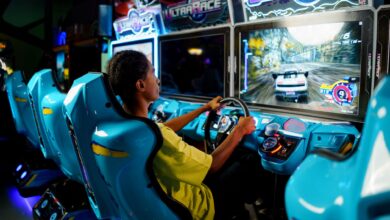 Teen playing a car racing video game at an indoor arcade entertainment center.