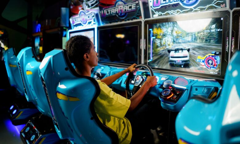 Teen playing a car racing video game at an indoor arcade entertainment center.