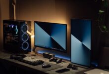 Modern dual monitor PC setup with tech gadgets on a sleek desk in a dimly lit room.