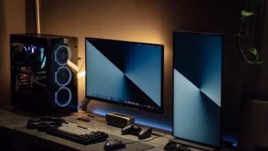 Modern dual monitor PC setup with tech gadgets on a sleek desk in a dimly lit room.