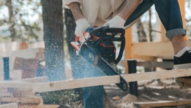 Outdoor scene of a man skillfully using a chainsaw on wood, showcasing carpentry expertise.