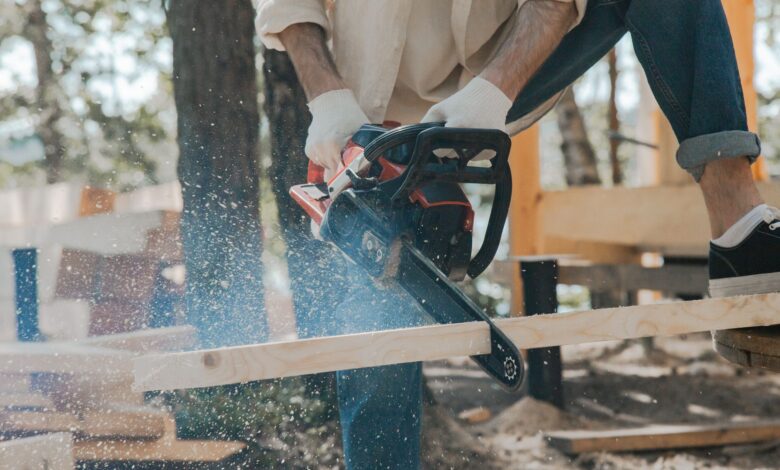 Outdoor scene of a man skillfully using a chainsaw on wood, showcasing carpentry expertise.