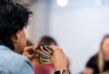 A person intently holds a variety of colorful game cards during indoor gathering.