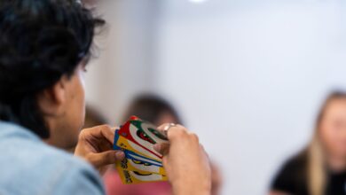A person intently holds a variety of colorful game cards during indoor gathering.