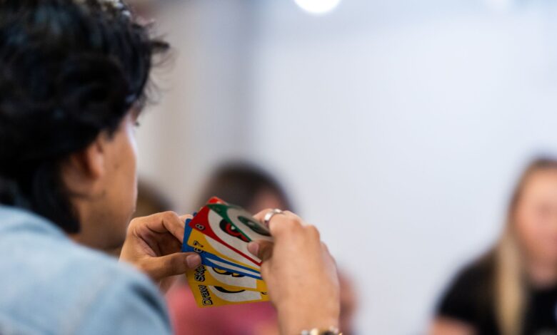 A person intently holds a variety of colorful game cards during indoor gathering.