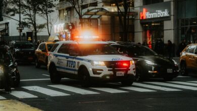 NYPD patrol car with flashing lights in downtown city traffic scene.