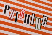 Conceptual image of the word 'Phishing' using cut-out letters on an orange striped background.