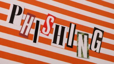 Conceptual image of the word 'Phishing' using cut-out letters on an orange striped background.