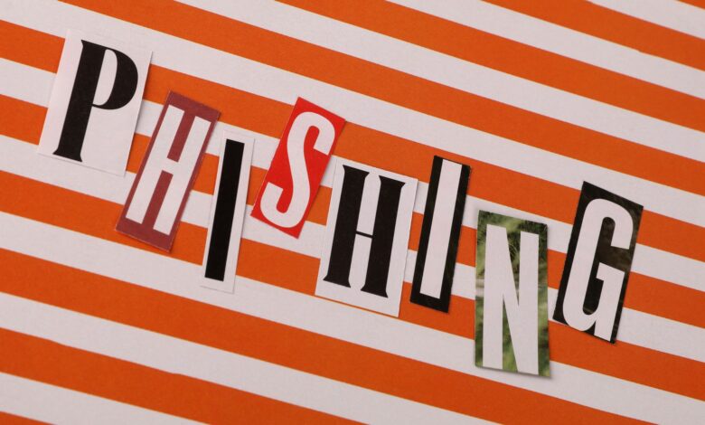 Conceptual image of the word 'Phishing' using cut-out letters on an orange striped background.