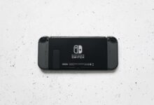 A close-up of a Nintendo Switch console placed on a textured marble surface, highlighting the device's sleek design.