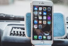 Close-up of a smartphone mounted on a car dashboard showing home screen with apps.