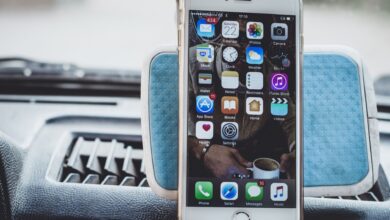 Close-up of a smartphone mounted on a car dashboard showing home screen with apps.
