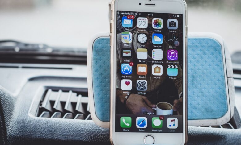 Close-up of a smartphone mounted on a car dashboard showing home screen with apps.