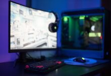 High-tech gaming setup featuring a curved monitor, RGB keyboard, and vibrant lighting.