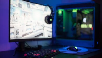 High-tech gaming setup featuring a curved monitor, RGB keyboard, and vibrant lighting.