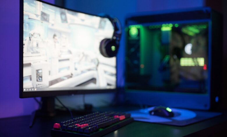 High-tech gaming setup featuring a curved monitor, RGB keyboard, and vibrant lighting.