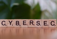 Wooden tiles spell 'CYBERSEC' against a soft-focused green background.