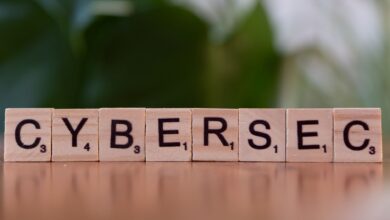 Wooden tiles spell 'CYBERSEC' against a soft-focused green background.