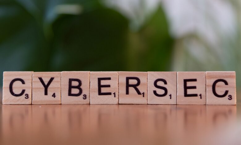 Wooden tiles spell 'CYBERSEC' against a soft-focused green background.