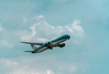 A commercial airplane flying through a cloudy blue sky, showcasing aviation travel.