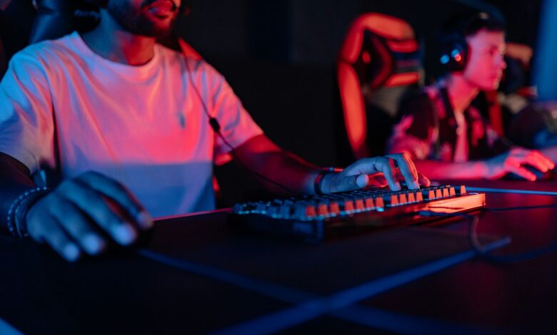 Two focused gamers in a neon-lit arena, wearing headphones and gaming intensely.