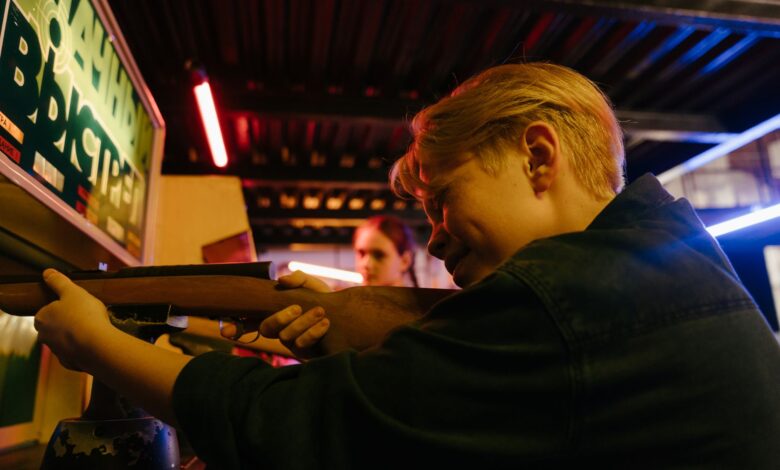 Group of teenagers at an arcade playing a retro shooting game and having fun together.