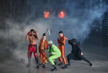 Dynamic group of diverse cosplayers striking action poses in an atmospheric indoor setting with smoke.