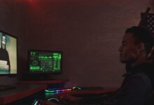 A cybersecurity professional monitors data systems in a dark room, emphasizing protection and vigilance.