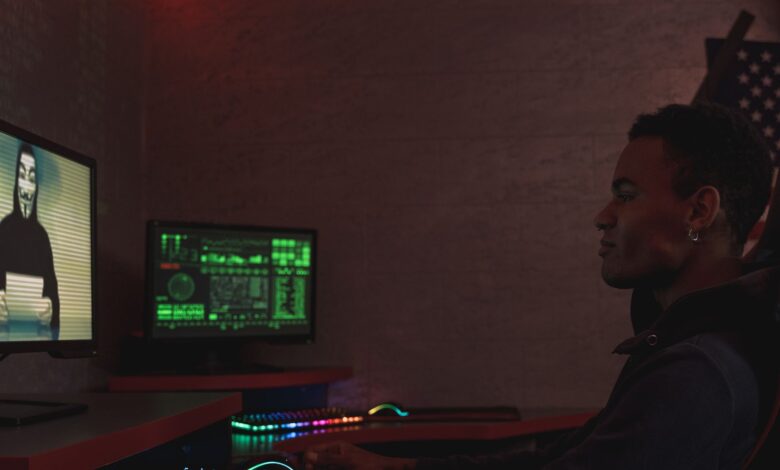 A cybersecurity professional monitors data systems in a dark room, emphasizing protection and vigilance.