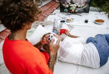 A couple relaxes outdoors playing video games together on a console.
