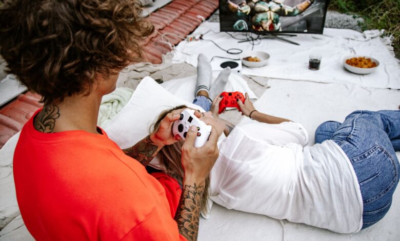 A couple relaxes outdoors playing video games together on a console.